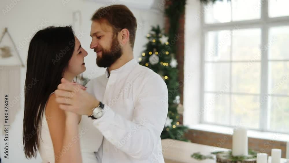 Happy attractive young couple in love dance together in their stylish apartment by the christmas tree Happy attractive young couple in love dance together in their stylish apartment by the christmas tree