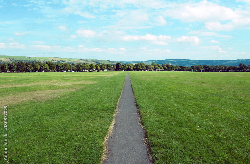 long straight foortpath ina park with grass lawn and distant trees in halifax yorkshire long straight foortpath ina park with grass lawn and distant trees in halifax yorkshire