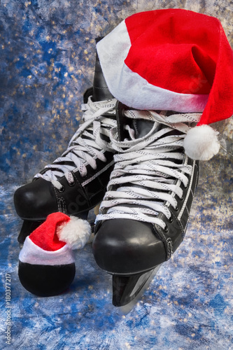 Hockey men's skates and puck close-up with Santa cap, concept of Christmas winter tournaments on a blue background