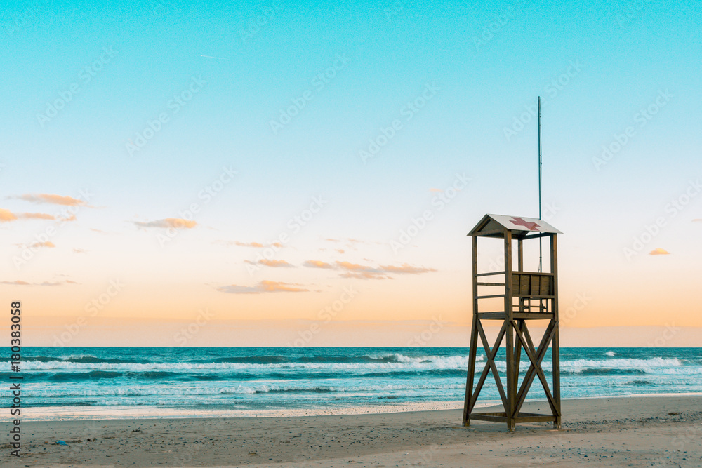Teal and orange mood of Beach sunrise with vintage lifeguard wooden tower