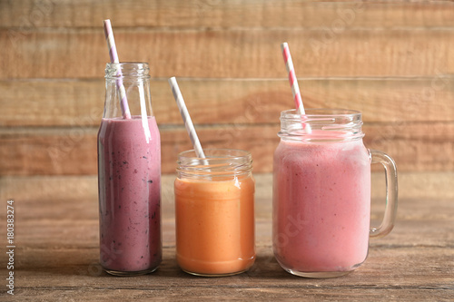 Glassware with yummy smoothie on wooden background