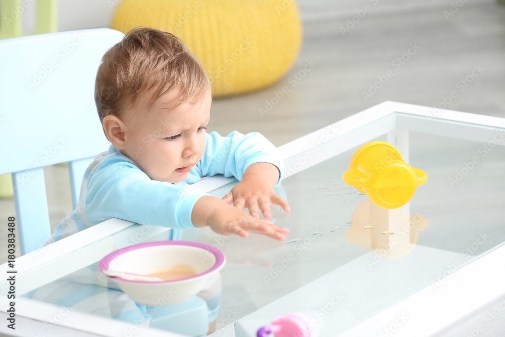 Adorable baby sitting at table indoors Adorable baby sitting at table indoors