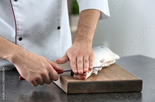 Chef cutting fresh salmon in kitchen