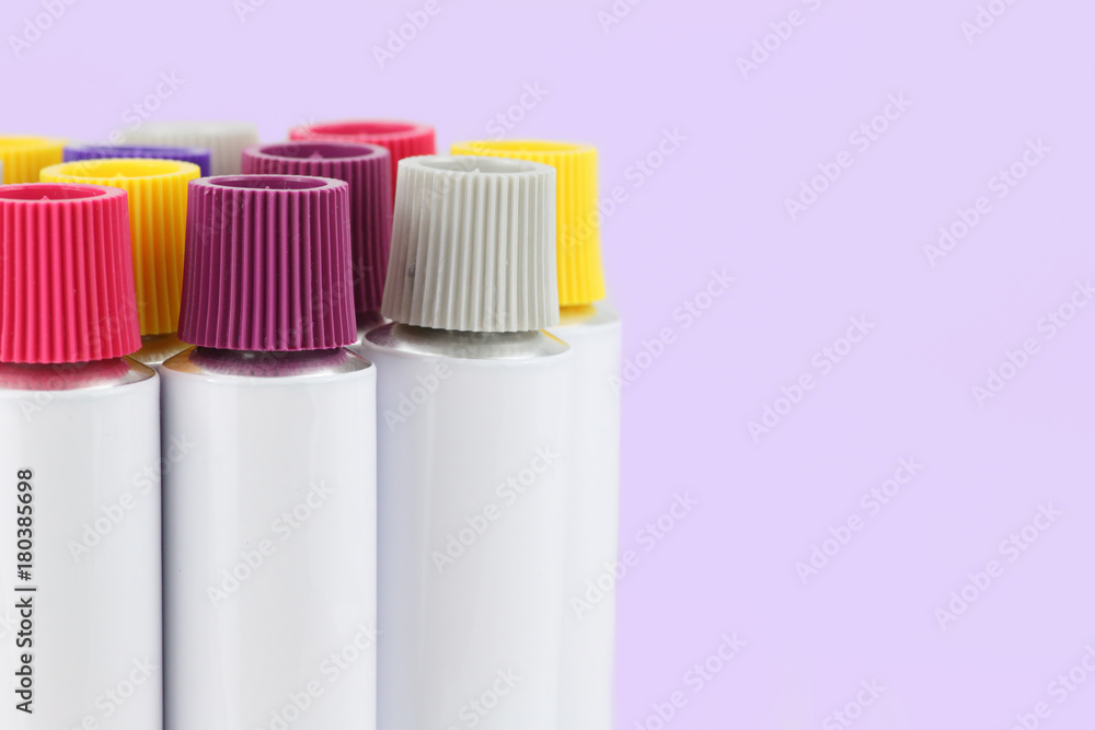 tubos de aluminio comprimible con tapones de rosca de colores en fondo lila con espacio para copia - obrazy, fototapety, plakaty 