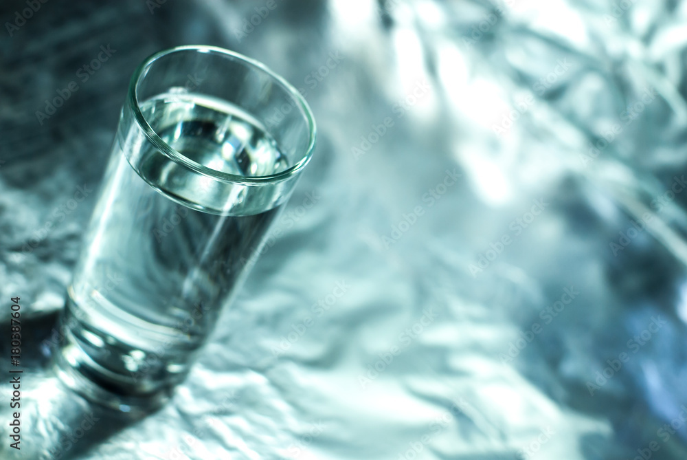 Glass of water on silver abstract background