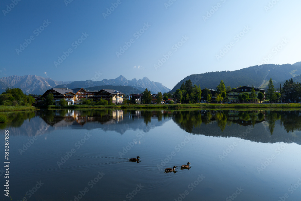 Fototapeta premium Pond in Alps with clear still water surface and swimming ducks. Seefeld, Austria
