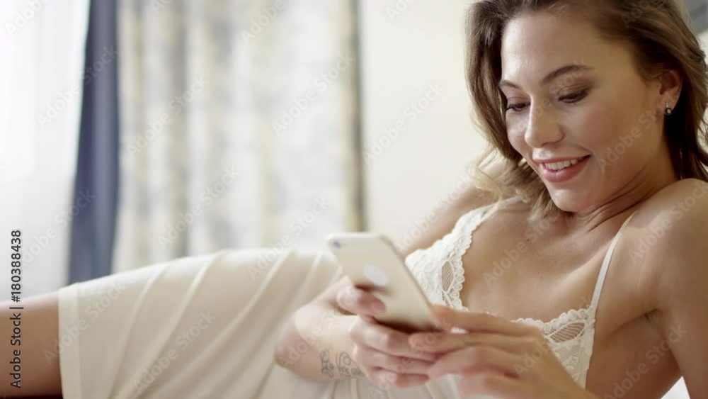 Tender woman lying on bed and using smartphone Tender woman lying on bed and using smartphone