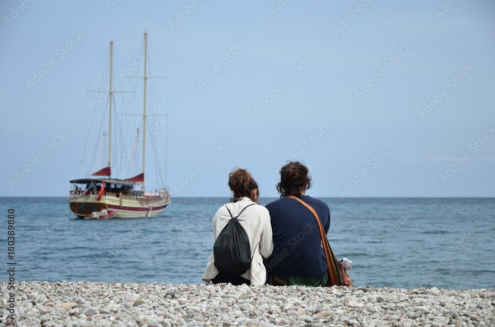 couple sitting at the beach on the background yacht couple sitting at the beach on the background yacht