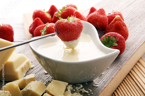 Foto Chocolate fondue melted with fresh strawberries and white chocolate pieces