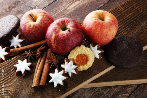 christmas cookies, apples, gingerbread and spice on brown background