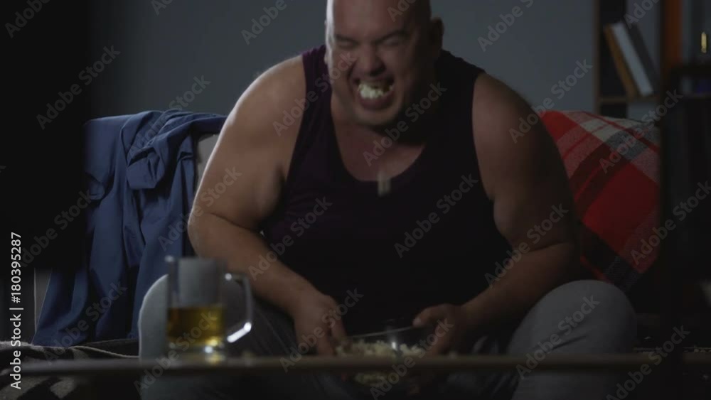 Man watching TV with popcorn and beer, messy careless lifestyle, food addiction Man watching TV with popcorn and beer, messy careless lifestyle, food addiction