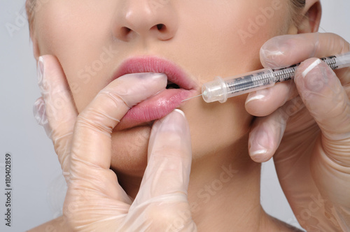 Close-up woman receives lip injection with syringe