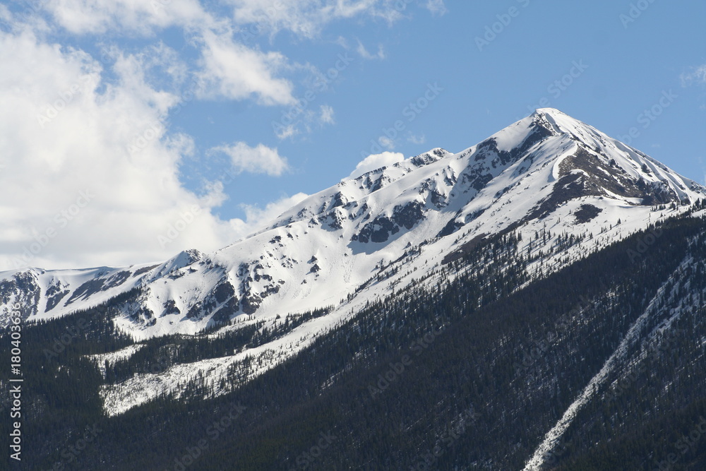 Snow covered Slopes against a blue sky with white puffy clouds