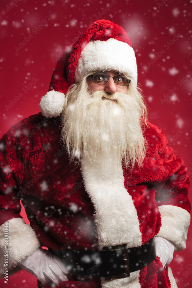 amazed santa claus standing with hands on waist while snowing amazed santa claus standing with hands on waist while snowing