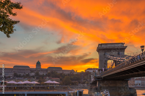 Budapest, Hungary - Beautiful dramatic golden sunset at Szechenyi Chain Bridge with Buda Castle Royal Palace at background photo