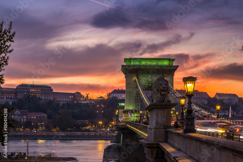 Budapest, Hungary - Beautiful dramatic golden sunset at Szechenyi Chain Bridge in green lights with Buda Castle Royal Palace at background photo