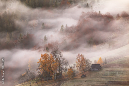 Mountain village in clouds of fog and smoke in the autumn morning