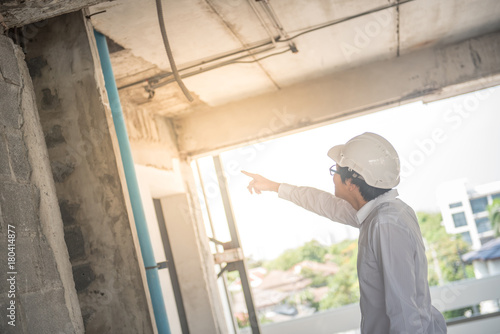 Engineer or Architect checking building while wearing a personal protective equipment safety helmet at construction site. Civil engineering, Architecture and building project concepts