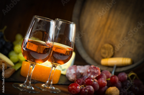 Glasses of rose wine cheeses grapesand barrel on brown wooden background photo