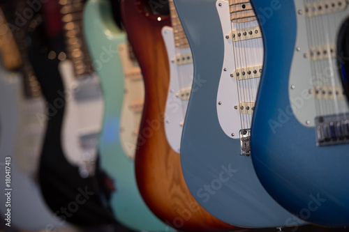 Many electric guitars hanging on wall in the shop