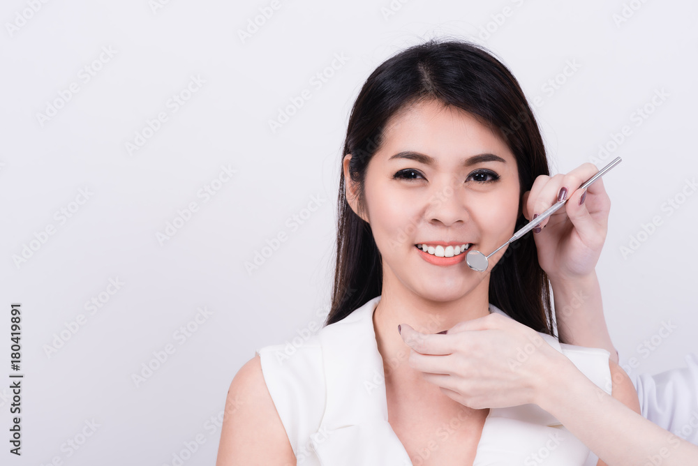 Portrait of smiling Asian woman with dentist examining her teeth isolated on white Portrait of smiling Asian woman with dentist examining her teeth isolated on white