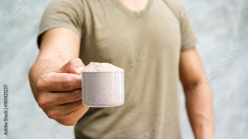 Man holding a whey protein on gray background.