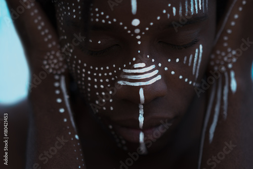 Portrait of a Sexy African man with traditional face paint and meditative expression photo