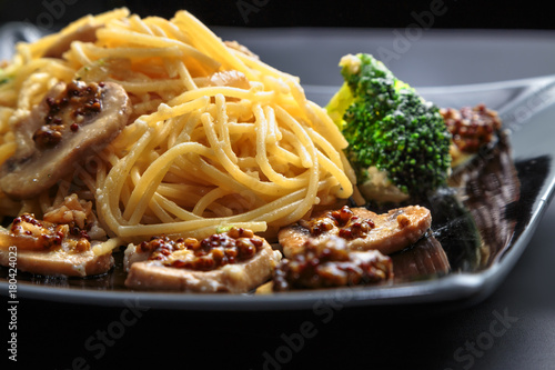 spaghetti with mushrooms and broccoli in a creamy sauce on a dark background