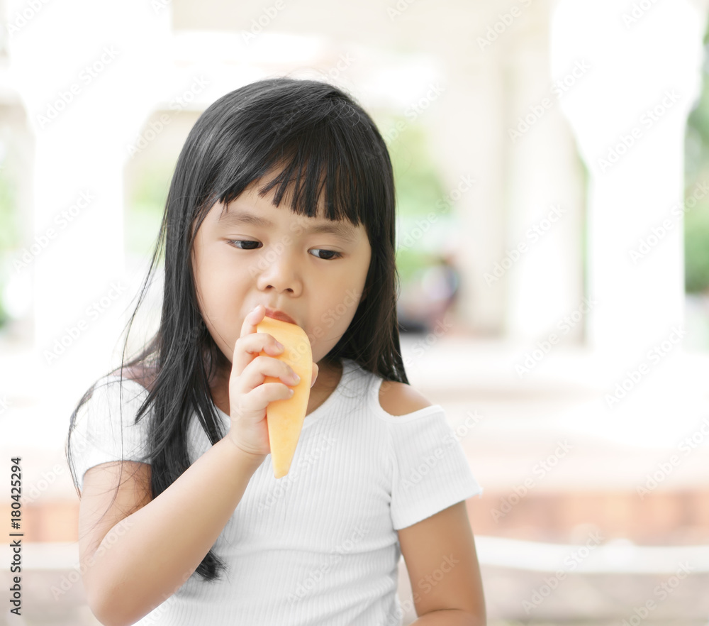 Asian children cute or kid girl enjoy eating cantaloupe melon fruit for healthy break snack at nature garden on holiday relax Asian children cute or kid girl enjoy eating cantaloupe melon fruit for healthy break snack at nature garden on holiday relax