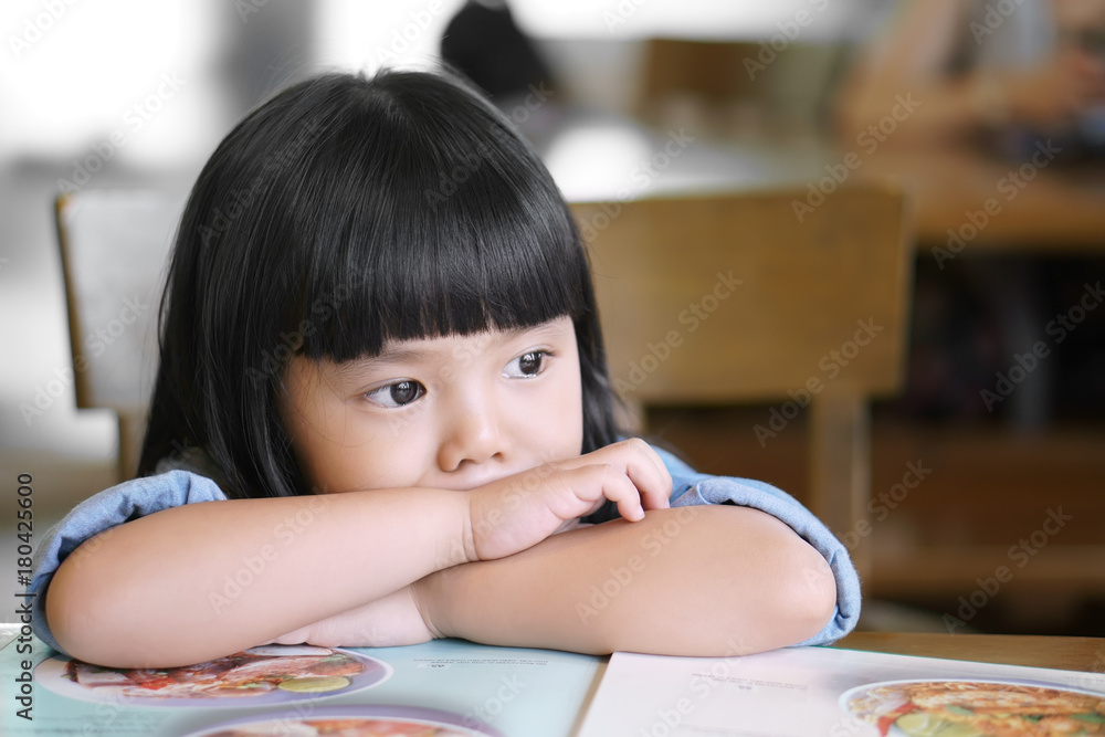 Asian children cute or kid girl lonely and sad with tears in the eye on food table because miss mom and dad or parents do not care with thinking something Asian children cute or kid girl lonely and sad with tears in the eye on food table because miss mom and dad or parents do not care with thinking something