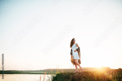 Young girl in a white dress with a hat and a wonderful sunset