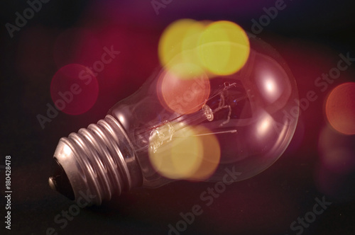 Bulb on black background with colourful blurred lights