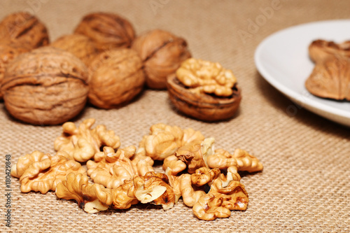 Opened and closed walnuts in a plate on a background of cloth and burlap