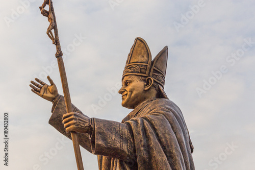 Ancient brass sculpture of Pope, the bishop of Rome with golden sunlight glare on the statue.