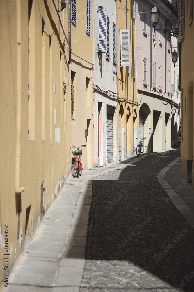 A red bicycle with a basket near the wall of the house on the small narrow street of the old town
