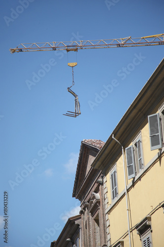Boom of a construction crane with metal braces against the blue sky above the houses
