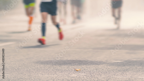 Low angle view of marathon runners running in sunny street, Blurred abstract motion group of runners, city street. Sport background. Fitness and healthy lifestyle, sport activity