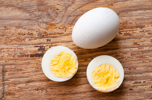 Vászonkép boiled egg cutout and raw egg with shell on wooden background