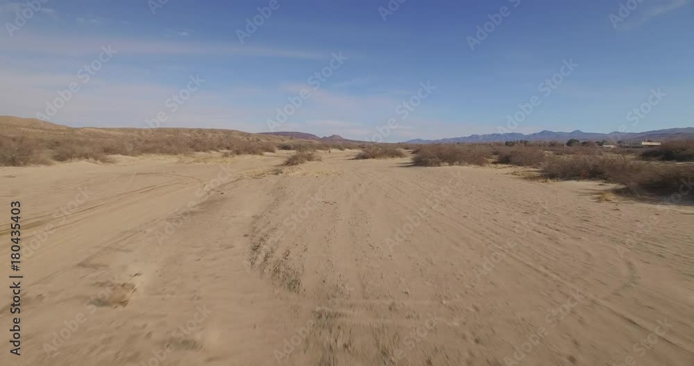 Fast tracking aerial of a man riding an ATV in the desert Fast tracking aerial of a man riding an ATV in the desert
