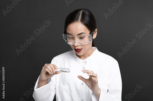 Horizontal shot of young Asian woman scientist analyzing cell culture samples, holding glass plate, collecting plant DNA in laboratory. Science, research, biochemistry and microbiology concept photo