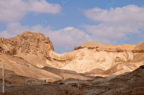 One unidentified tourist on hiking trail approaching to mountain pass in Negev desert.