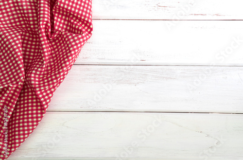 The Crumpled red checkered tablecloth or napkin on empty white wooden table with copy space for food cooking menu background concept , top view or overhead shot