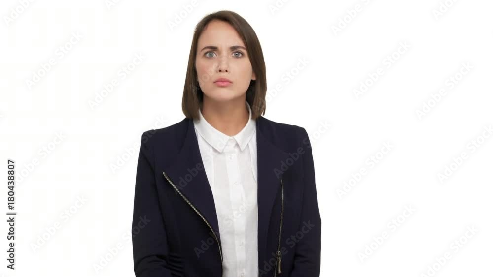 portrait of caucasian short-haired woman with beautiful blue eyes wearing business suit looking at camera with strict gaze holding index finger on lips asking to keep silence over white background in portrait of caucasian short-haired woman with beautiful blue eyes wearing business suit looking at camera with strict gaze holding index finger on lips asking to keep silence over white background in