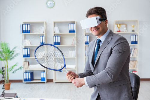 Businessman playing virtual reality tennis in office with VR gog