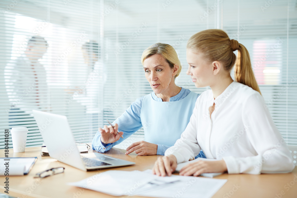 Young subordinate and mature employer discussing online presentation at meeting Young subordinate and mature employer discussing online presentation at meeting