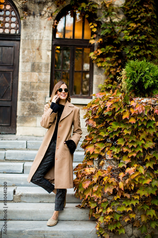 Fototapeta premium Modern woman using mobile phone at autumn outdoor