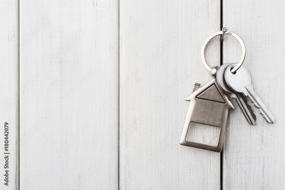 Bunch of keys with house shaped keychain on white wood Bunch of keys with house shaped keychain on white wood