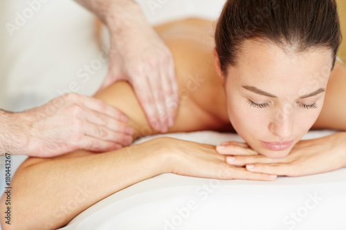 Young woman taking pleasure while having massage of her body