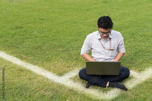 business man is sitting work with computer laptop on soccer field. working concept. copy space for conceptual message.
