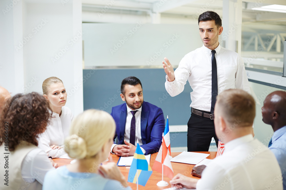 Confident politician voicing his point of view to colleagues from other countries at briefing Confident politician voicing his point of view to colleagues from other countries at briefing
